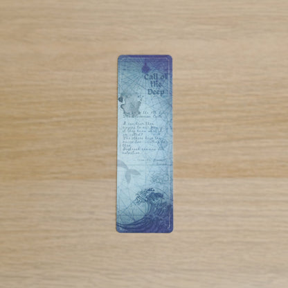A rectangular vintage-style bookmark  'Call of the Deep' wave illustration and text, displayed vertically on a light wood grain background.