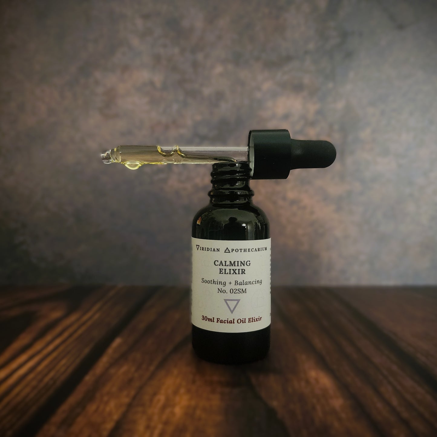 Bottle of 'Calming Elixir' by Viridian Apothecarium, with dropper on a wooden surface