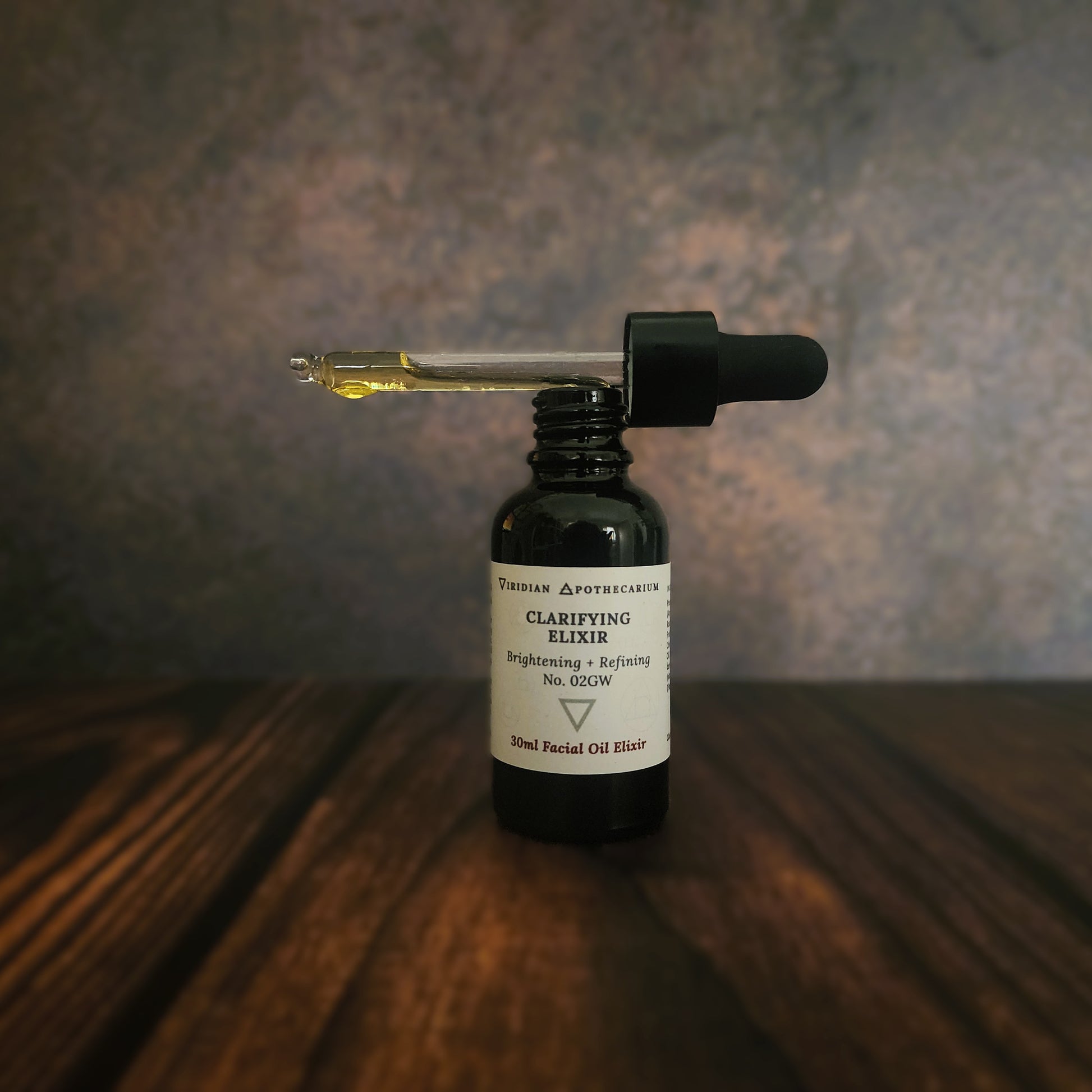 Bottle of Clarifying Elixir with dropper on a wooden surface, by Viridian Apothecarium
