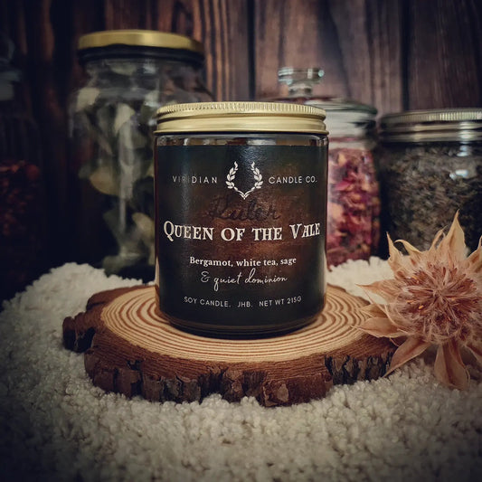 Queen of the Vale soy fantasy candle by Viridian Candle Co, on an apothecary shelf with wood, furs, dried botanicals - elegant fantasy-inspired candle with bergamot and oakmoss