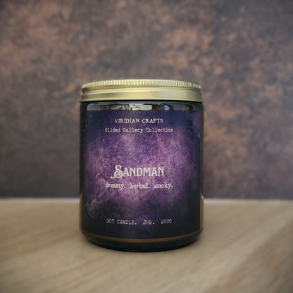 A jar candle with a purple watercolor-style label reading 'Sandman' and 'Viridian Crafts', set on a light wood surface against a textured brown background.