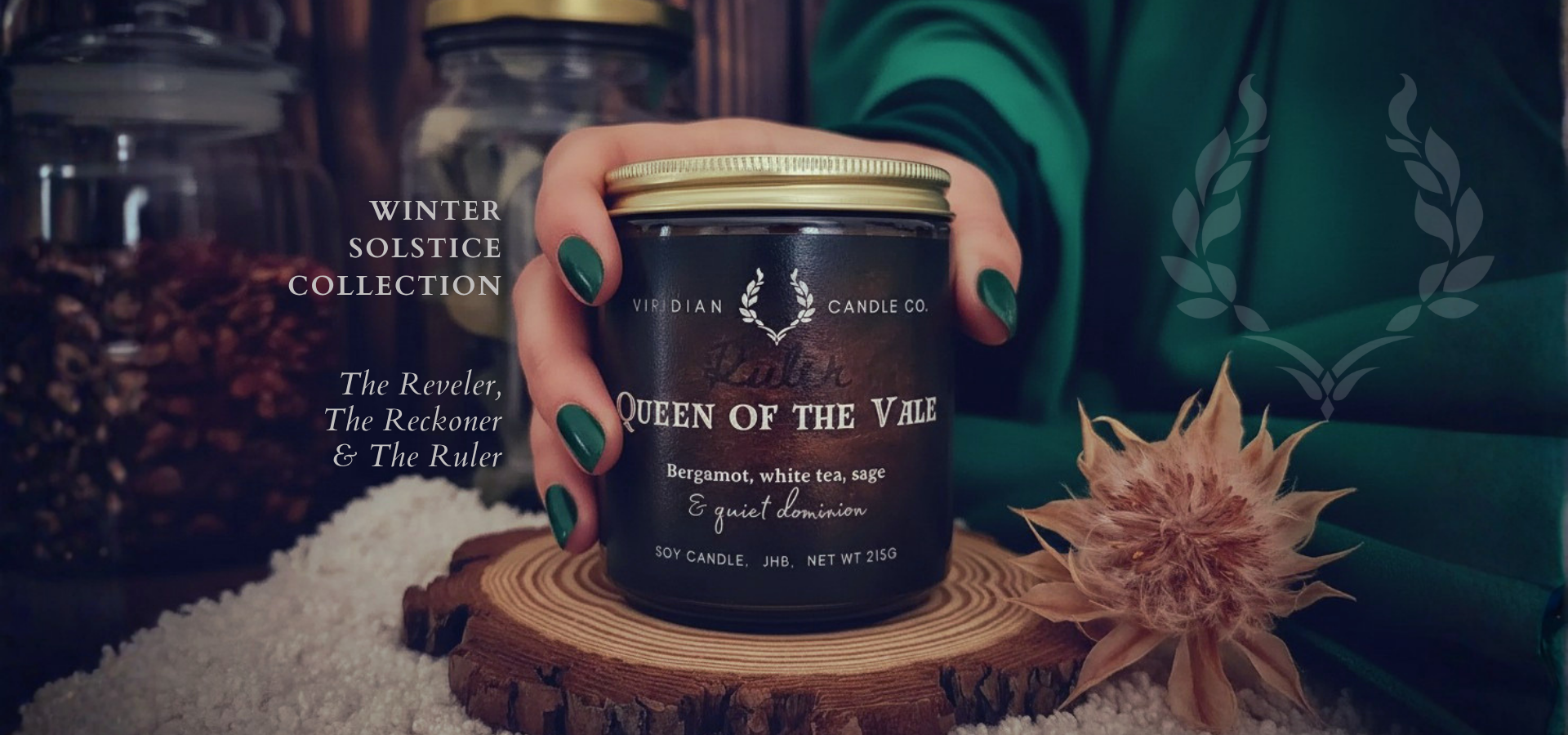 Hand holding a candle labeled 'Queen of the Vale' from Hidian Candle Co. with winter solstice collection text.